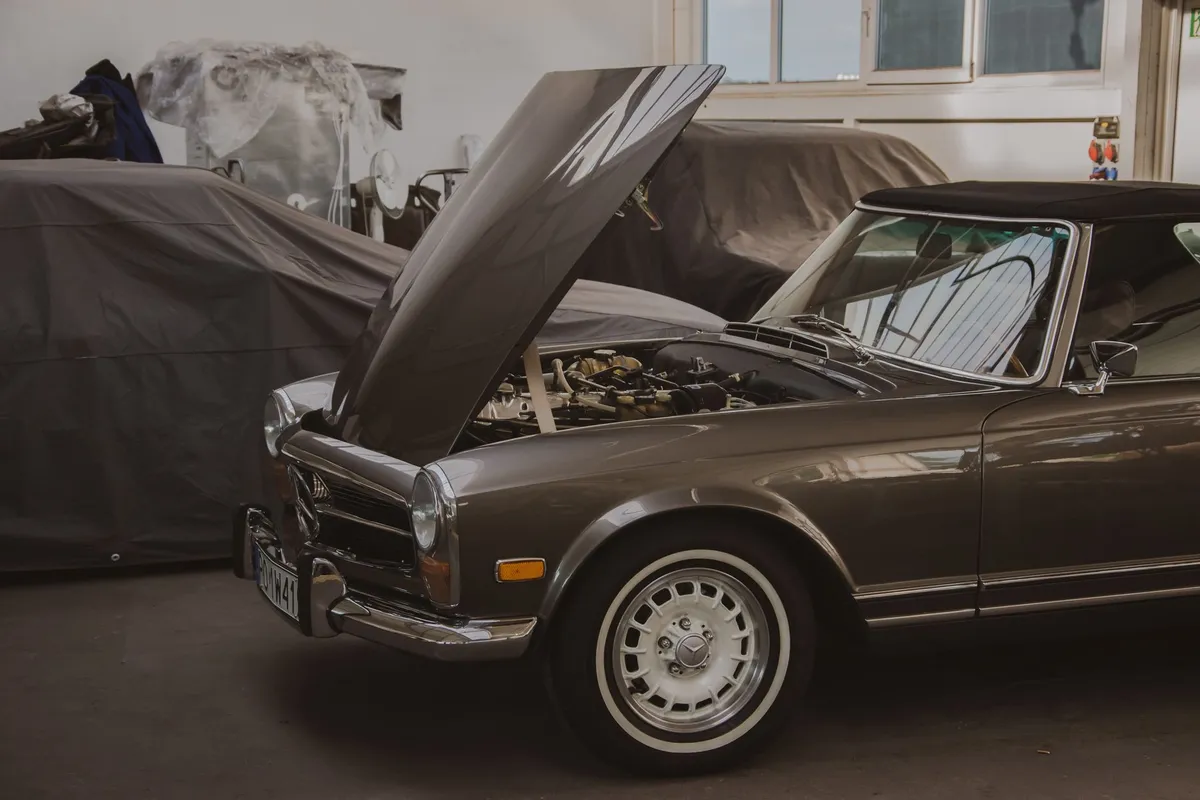 A restored classic car parked in a garage with its hood open