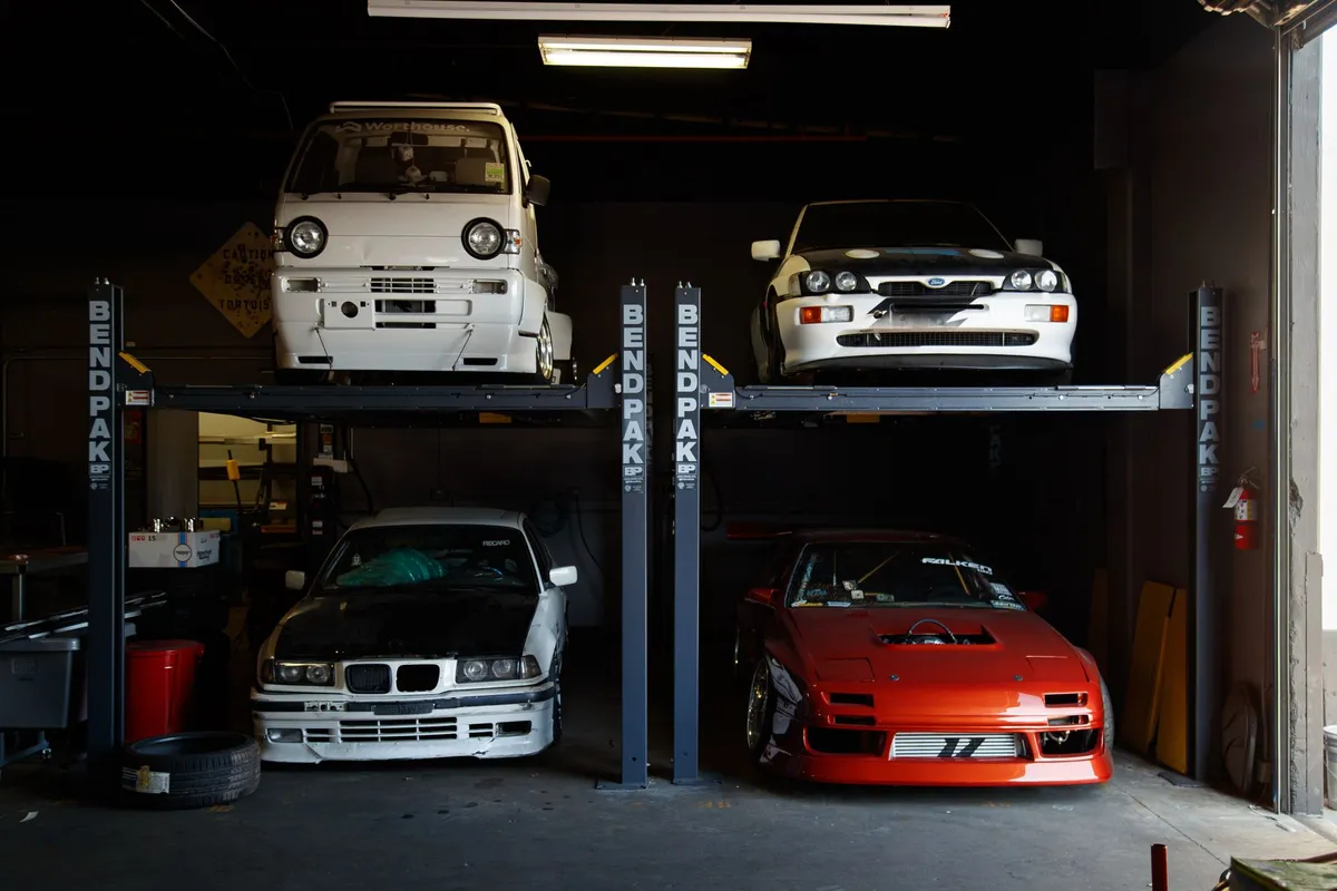 Modified cars on two-post lifts inside a custom car garage workshop