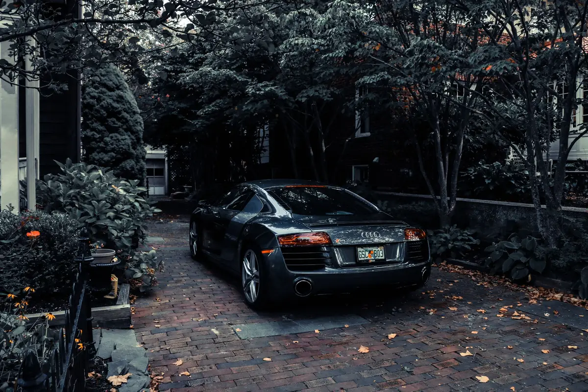 A car parked in a quiet residential driveway surrounded by trees