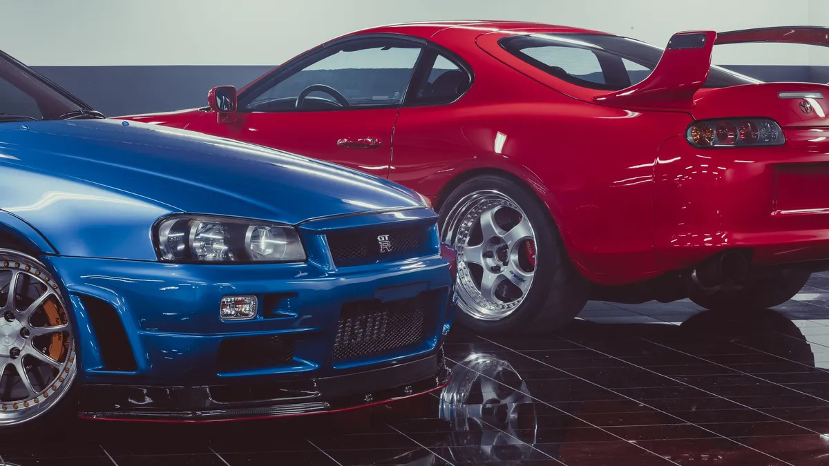 A blue Nissan Skyline GT-R and a red Toyota Supra parked side by side